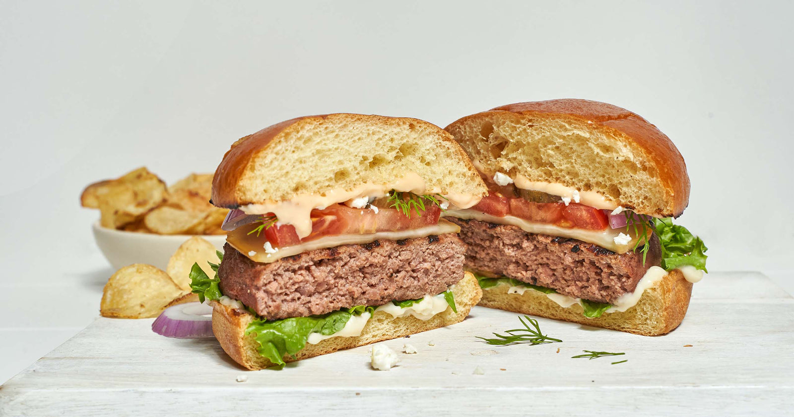 Close Up of Bump Burger Assembled with Bowl of Chips in Background